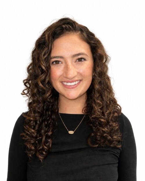 Photo of smiling woman with long curly hair in a black long sleeve top